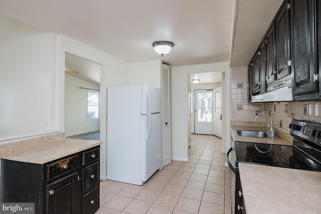 kitchen with stainless steel electric stove, dark cabinets, freestanding refrigerator, and a sink