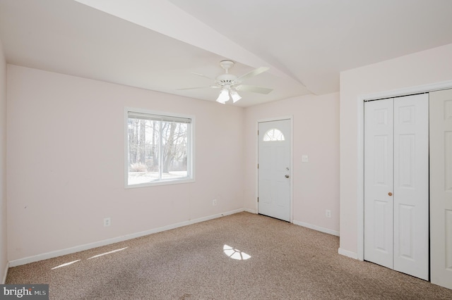 carpeted entryway featuring baseboards and ceiling fan