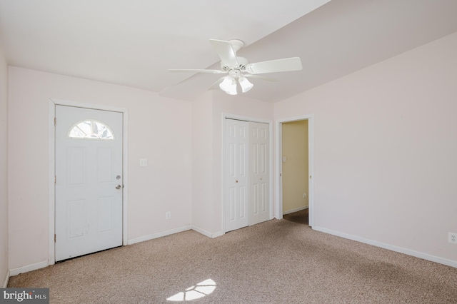 carpeted foyer with a ceiling fan and baseboards