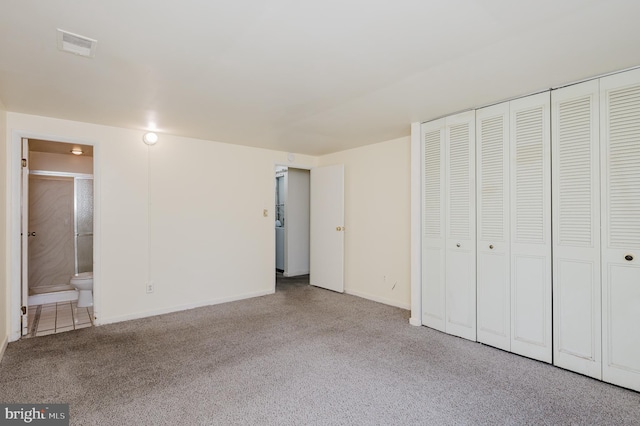 unfurnished bedroom with visible vents, baseboards, carpet, a closet, and ensuite bath