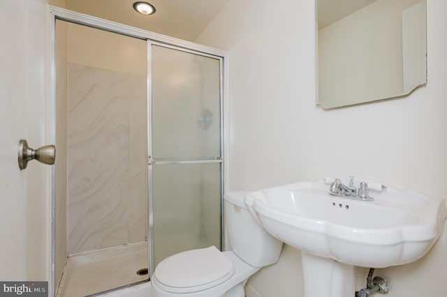 bathroom featuring a sink, toilet, and a stall shower