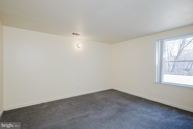 empty room with a wealth of natural light, baseboards, and dark colored carpet