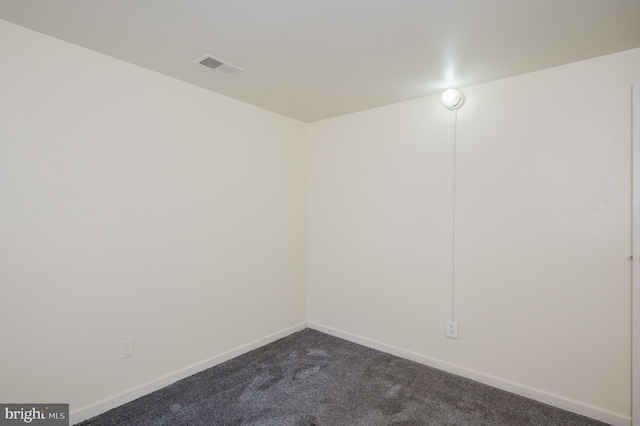 spare room with visible vents, dark carpet, and baseboards