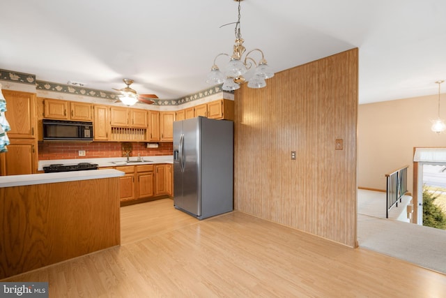 kitchen featuring light countertops, light wood-style flooring, a sink, black microwave, and stainless steel fridge with ice dispenser