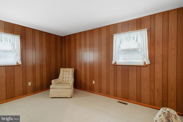 unfurnished room featuring wood walls, carpet, visible vents, and baseboards