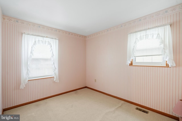 carpeted empty room with baseboards, plenty of natural light, visible vents, and wallpapered walls