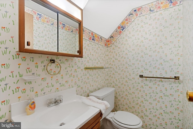 bathroom with a sink, toilet, and wallpapered walls