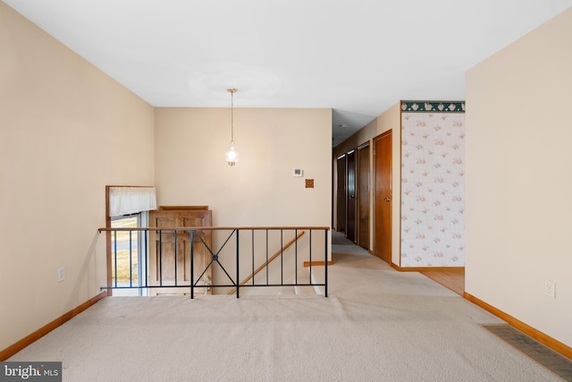 carpeted spare room with visible vents and baseboards