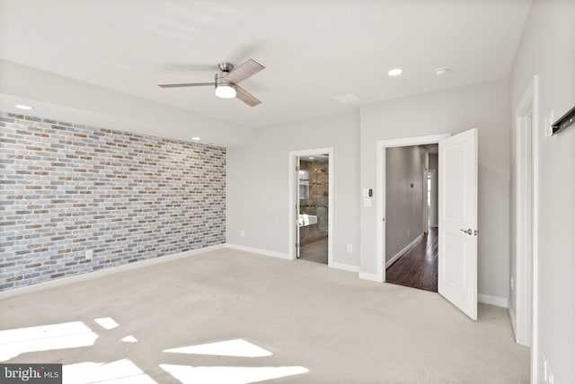 unfurnished bedroom with baseboards, brick wall, carpet floors, ensuite bath, and an accent wall