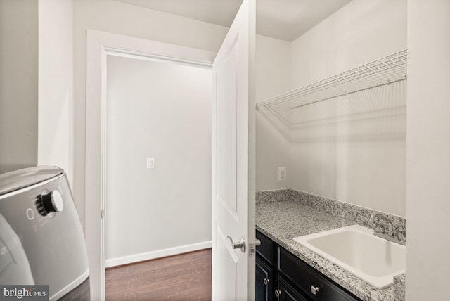 laundry room featuring dark wood finished floors, laundry area, baseboards, and a sink