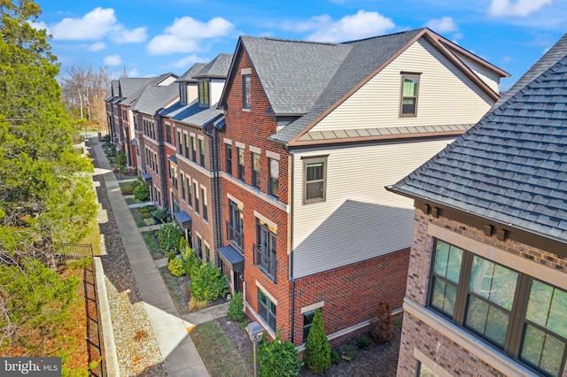 view of side of property featuring brick siding and a shingled roof