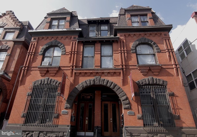 view of front of house with mansard roof and brick siding