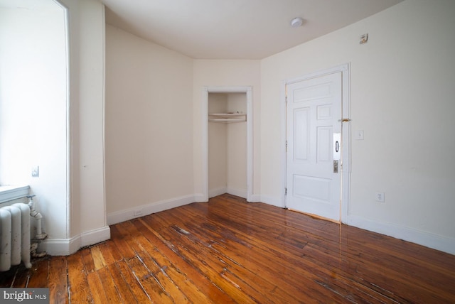 unfurnished bedroom featuring radiator, hardwood / wood-style floors, a closet, and baseboards