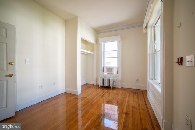 unfurnished bedroom with baseboards, wood finished floors, and radiator