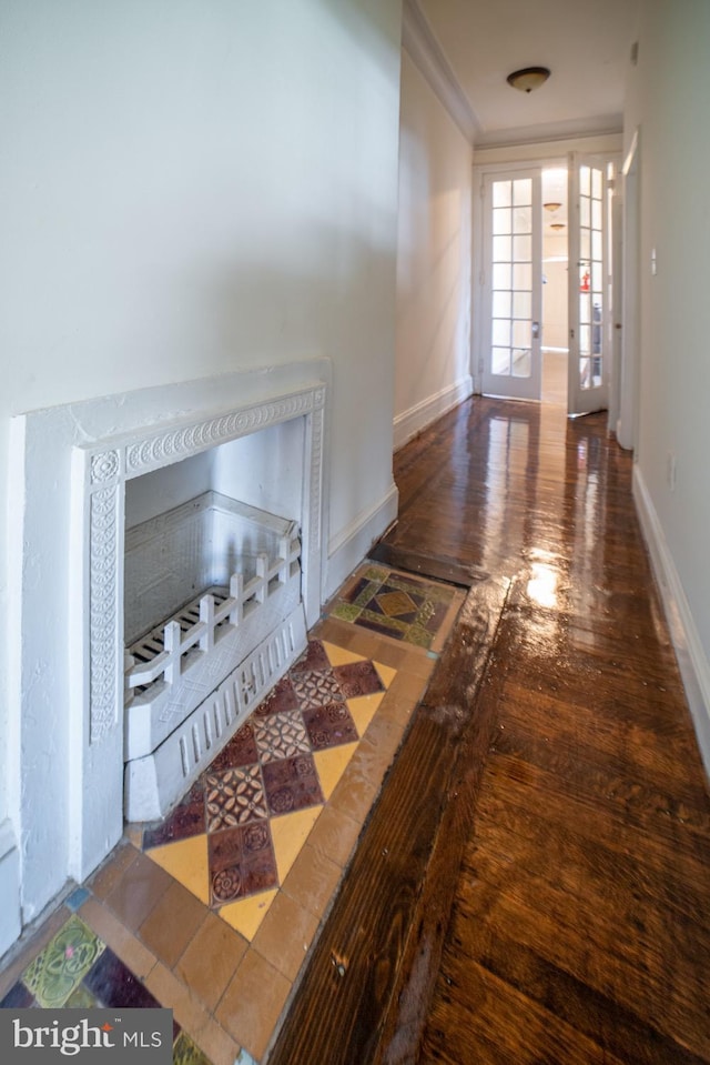 corridor featuring ornamental molding, baseboards, and wood finished floors