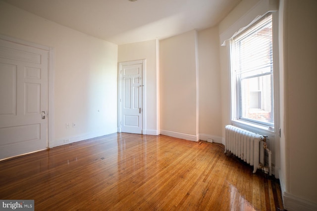 interior space with baseboards, multiple windows, radiator heating unit, and light wood-style floors