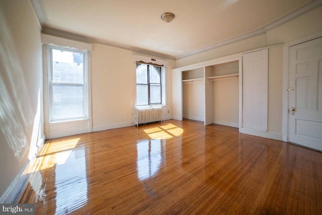 unfurnished bedroom featuring crown molding, baseboards, hardwood / wood-style flooring, and radiator