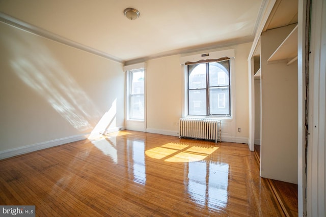 empty room with radiator, baseboards, and wood finished floors