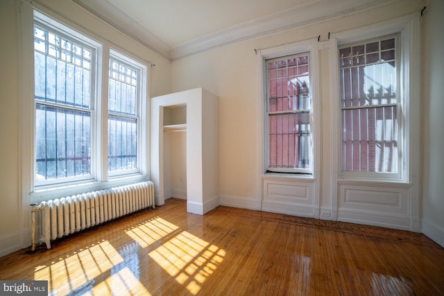 entryway with plenty of natural light, radiator, crown molding, and wood finished floors