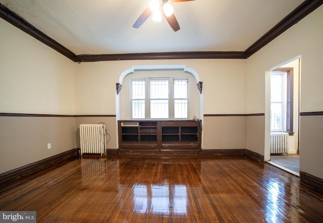 spare room with wood-type flooring, crown molding, and radiator heating unit