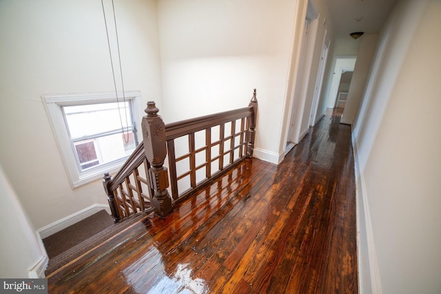 corridor with hardwood / wood-style floors, an upstairs landing, and baseboards