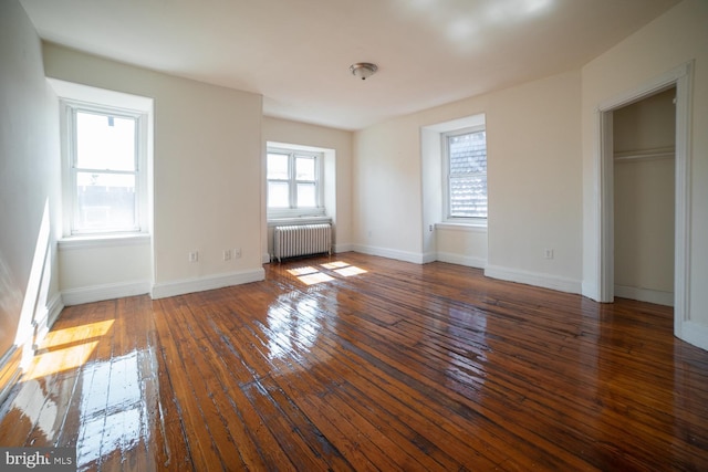 unfurnished bedroom featuring baseboards, hardwood / wood-style floors, and radiator