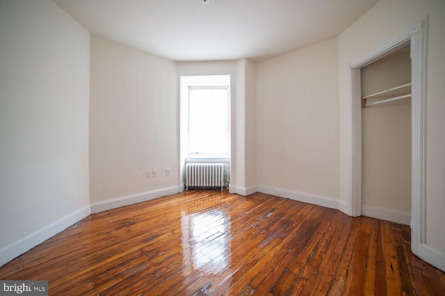 unfurnished bedroom with radiator, hardwood / wood-style flooring, and baseboards