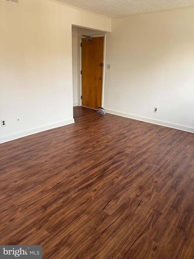 unfurnished room featuring dark wood-style flooring, visible vents, a textured ceiling, and baseboards