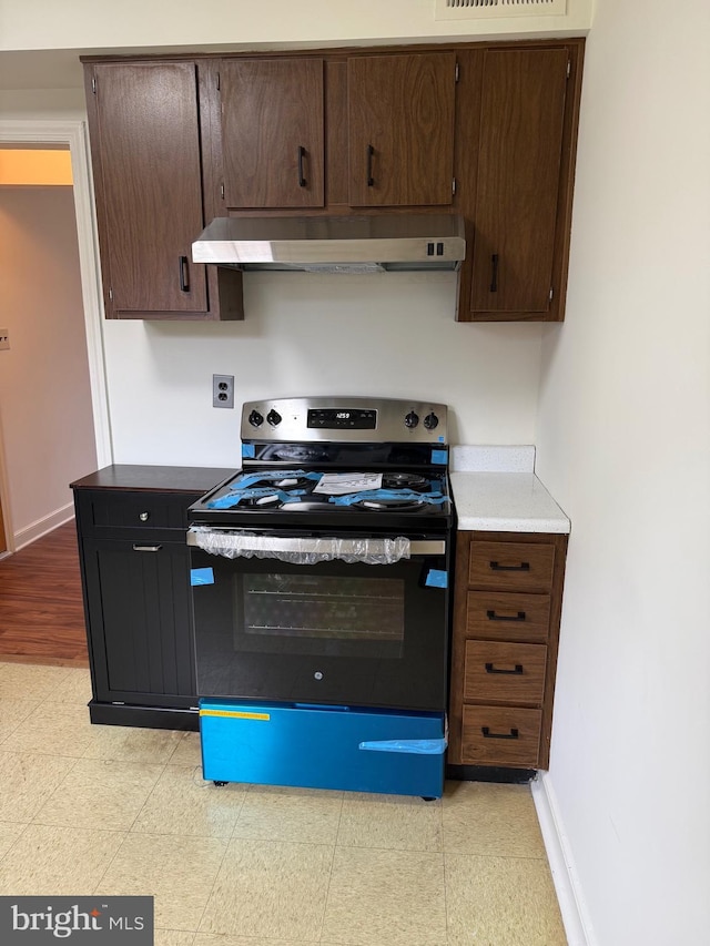 kitchen with baseboards, exhaust hood, dark brown cabinetry, and stainless steel range with electric cooktop