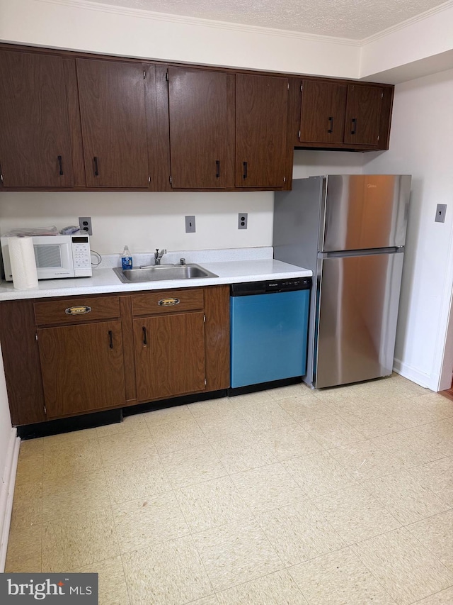 kitchen with dishwashing machine, a sink, light countertops, freestanding refrigerator, and light floors