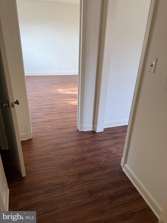 corridor featuring dark wood-style floors and baseboards