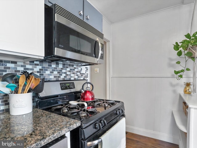 kitchen featuring dark stone counters, appliances with stainless steel finishes, dark wood-style flooring, and backsplash