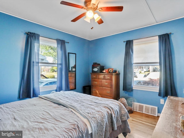 bedroom with a ceiling fan, visible vents, and wood finished floors