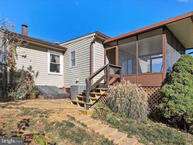 exterior space featuring central AC unit, a chimney, and a sunroom