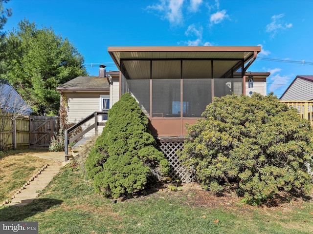 view of property exterior with a sunroom, a chimney, and fence