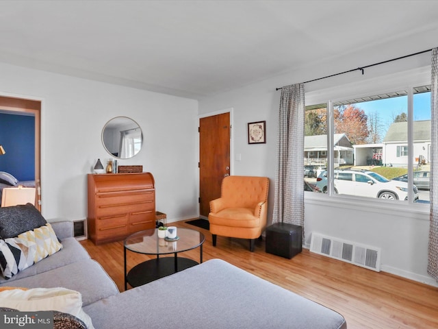 living room with baseboards, visible vents, and wood finished floors