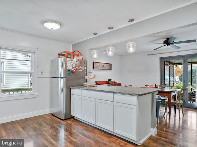 kitchen featuring baseboards, dark wood-style flooring, freestanding refrigerator, a peninsula, and white cabinetry