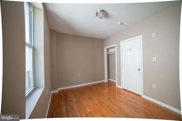 unfurnished bedroom featuring a closet, light wood-style flooring, and baseboards