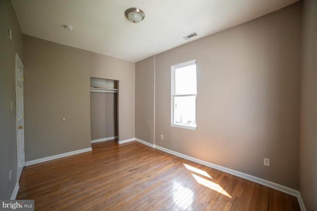 unfurnished bedroom with baseboards, visible vents, a closet, and wood finished floors