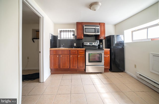 kitchen with brown cabinets, light tile patterned floors, stainless steel appliances, tasteful backsplash, and baseboard heating