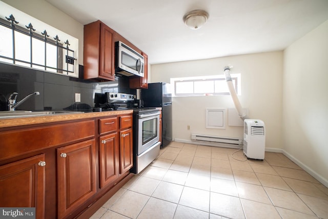 kitchen featuring stainless steel appliances, tasteful backsplash, a baseboard heating unit, light tile patterned flooring, and a sink