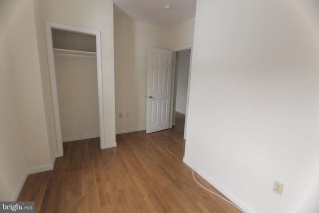 unfurnished bedroom featuring light wood-type flooring, a closet, and baseboards