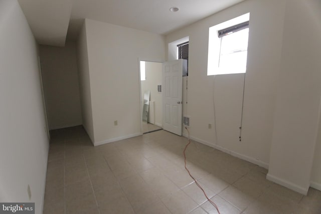 empty room with light tile patterned floors and baseboards