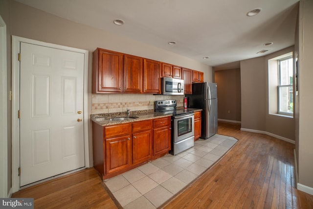 kitchen featuring a sink, light wood-style floors, stainless steel appliances, and backsplash