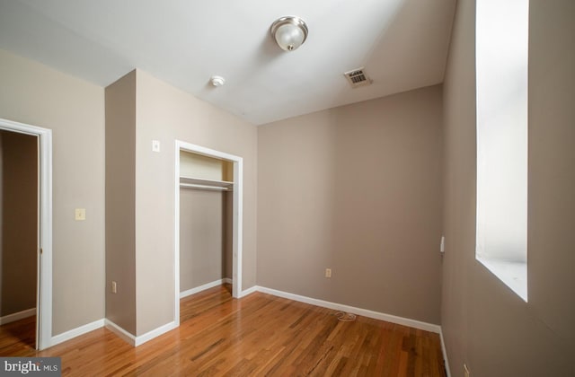 unfurnished bedroom featuring a closet, visible vents, light wood-style flooring, and baseboards