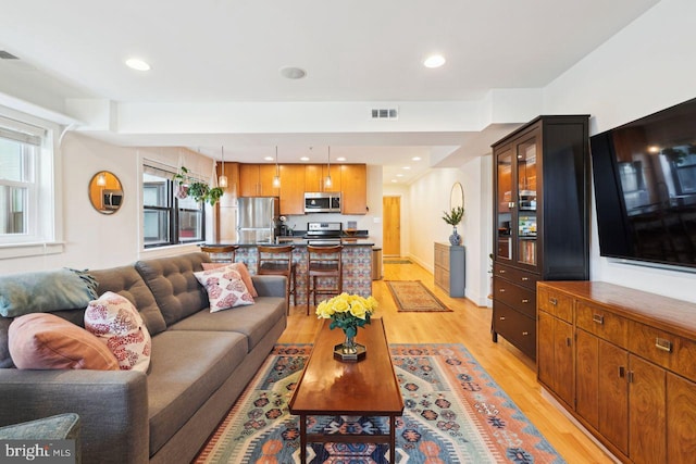 living area with light wood-style flooring, visible vents, baseboards, and recessed lighting