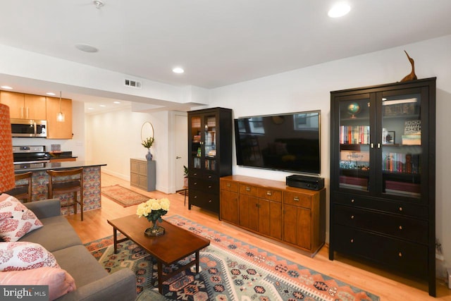 living area with light wood finished floors, visible vents, and recessed lighting