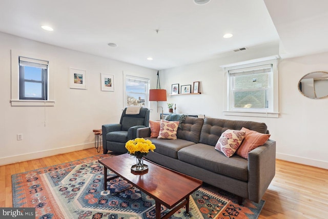 living area with light wood-style floors, recessed lighting, visible vents, and baseboards