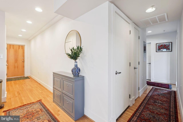 hallway featuring light wood-style flooring, visible vents, baseboards, and recessed lighting