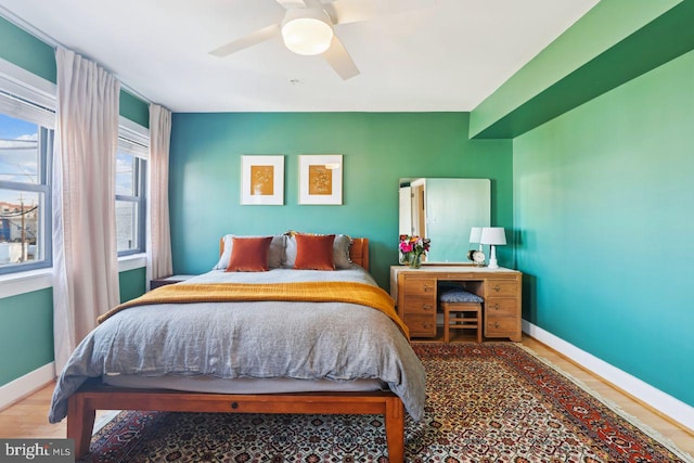 bedroom with ceiling fan, wood finished floors, and baseboards